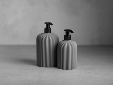 SVEA Seifenspender in Steingrau, 250 ml und 500 ml, mit schwarzer Pumpe und feiner vertikaler Struktur.